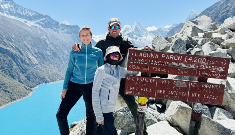 Une famille française souriante devant le panneau d’altitude au Lac Parón (4 300 m), avec la chaîne enneigée en arrière-plan.