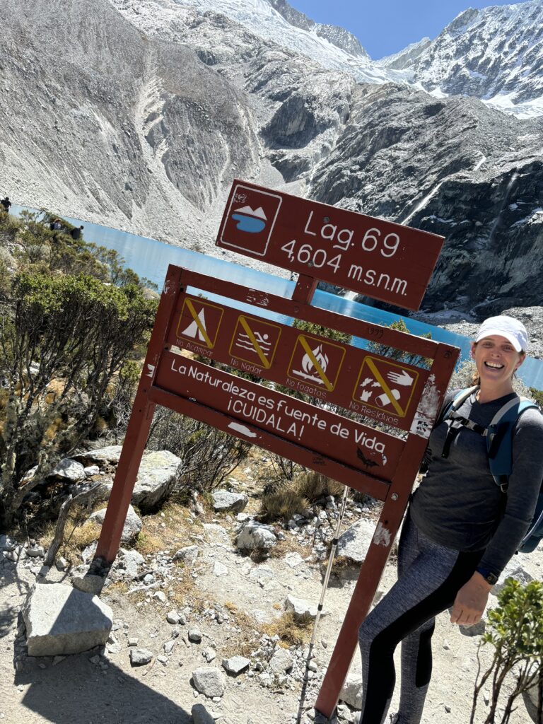 Armelle, souriante, pose seule devant le panneau de la Laguna 69 à 4 600 m d’altitude.