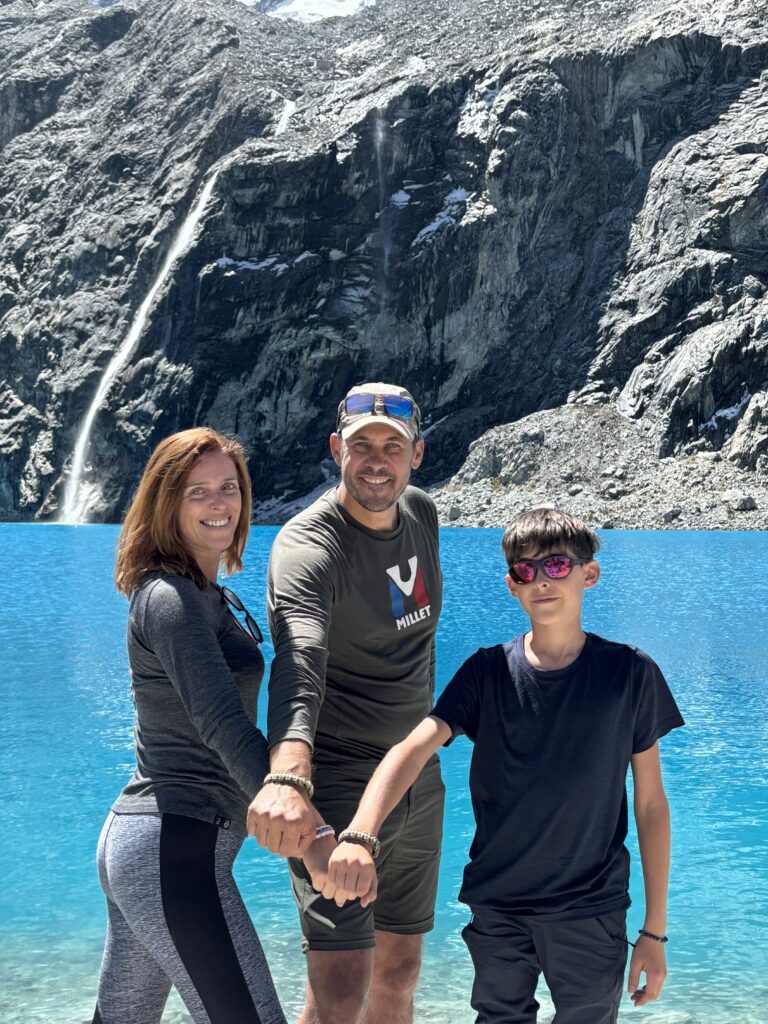 Une famille souriante et heureuse devant la Laguna 69 turquoise, après avoir battu son record d’altitude.