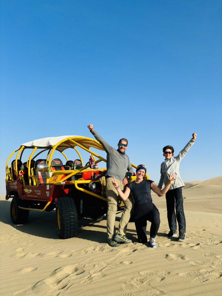 Une famille devant un buggy rouge dans le désert de sable d’Huacachina.