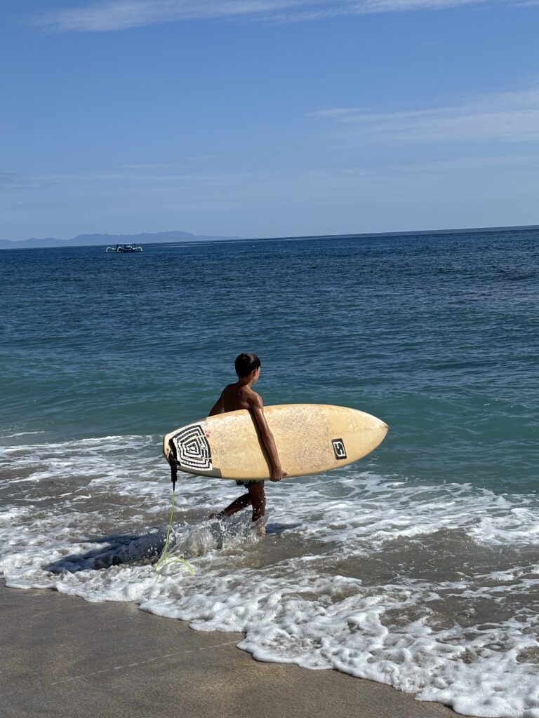 Célian avec une planche de surf en Indonésie.