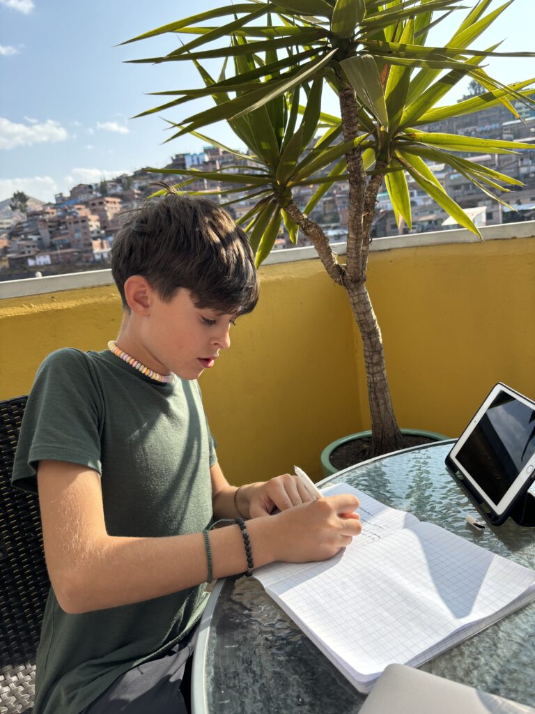 Célian écrit dans son cahier sur un rooftop à Cusco avec sa tablette.