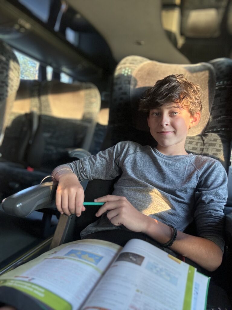 Célian fait ses devoirs dans un bus en voyage.