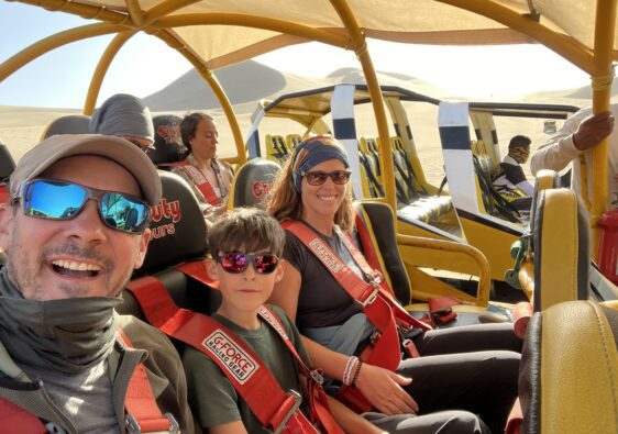 Une famille dans un buggy rouge et jaune dans le désert de sable d’Huacachina.