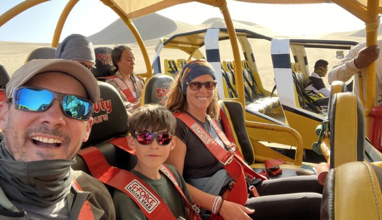 Une famille dans un buggy rouge et jaune dans le désert de sable d’Huacachina.