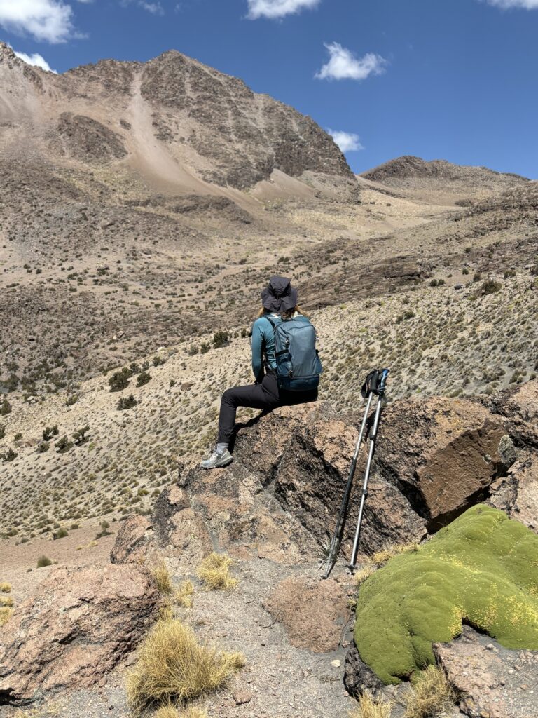 Randonneuse assise sur un rocher, contemplant les montagnes du parc national Sajama.