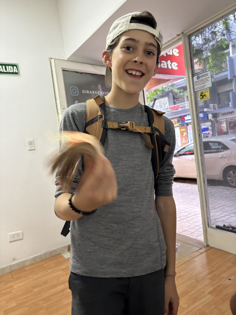 Jeune voyageur souriant tenant une liasse de billets de pesos argentins après un retrait à Buenos Aires, symbole de l’inflation et du coût de la vie en Argentine.